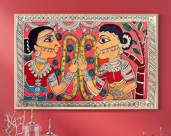 May include: A colorful painting depicting two women in traditional Indian clothing, with intricate details and vibrant colors. The women are facing each other, with a snake-like design between them. The painting is framed and has a white background.