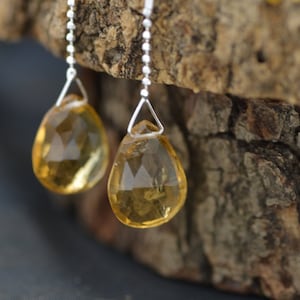 Puede incluir: Un par de pendientes de plata con piedras de citrino amarillo en forma de lágrima.