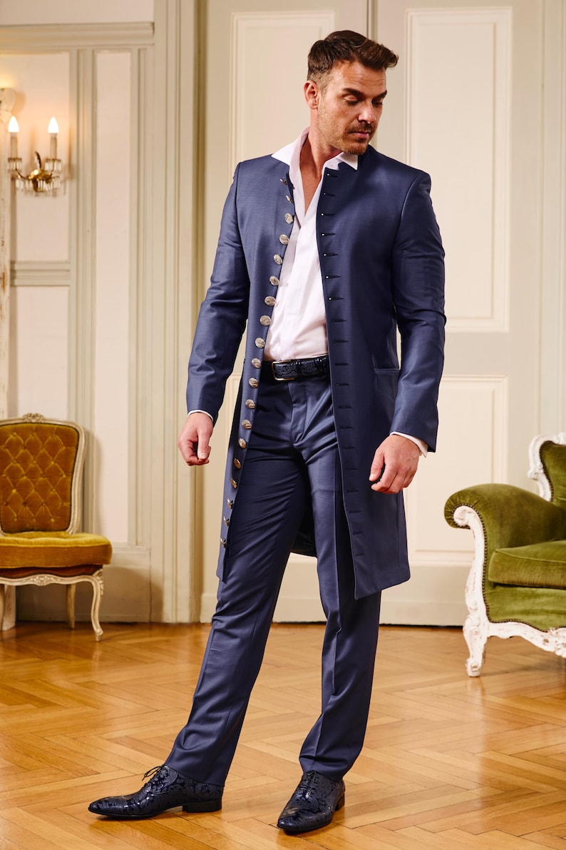 May include: A navy blue suit with a long coat, featuring gold buttons and a white collared shirt. The suit is paired with matching trousers and black dress shoes. The outfit is formal and elegant.