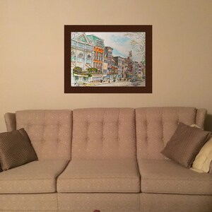 May include: A watercolour painting depicting a city street scene with buildings, trees, and people walking. The buildings are painted in shades of brown, yellow, and green. The trees are painted in shades of green and brown. The people are painted in shades of blue, green, and brown.