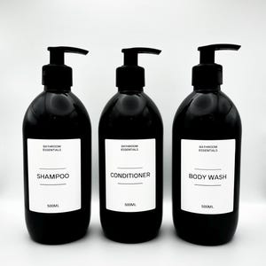 May include: Three black pump bottles for bathroom use, labelled "Shampoo", "Conditioner", and "Body Wash". Each bottle has a white label with black text and the words "Bathroom Essentials". Each bottle holds 500ml.