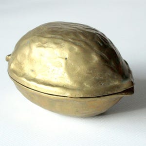 May include: A gold-coloured metal nutcracker shaped like a walnut.