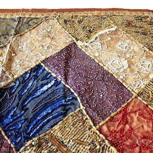 May include: A patchwork quilt with a variety of textures and colors, including brown, gold, blue, purple, and red. The quilt is made of different fabrics, including lace, sequins, and beads.