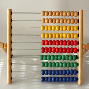 May include: A wooden abacus with colorful beads. The beads are arranged in rows of ten, with each row a different color: brown, yellow, red, green, and blue.