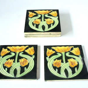Peut inclure: Ensemble de quatre carreaux de céramique carrés avec un motif floral. Les carreaux présentent un fond noir avec des fleurs jaunes et des tiges vertes. Les carreaux mesurent environ 10 cm de côté.
