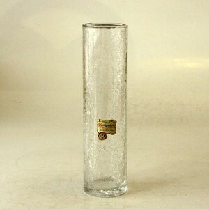 May include: A clear glass vase with a textured surface. The vase has a label that reads "Handgemacht Munchen-Gern"