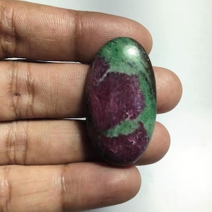 May include: An oval-shaped cabochon gemstone featuring a polished surface with a distinct color combination of deep magenta-red patches set against a vibrant, mottled green background, showcasing natural mineral inclusions and a smooth texture.