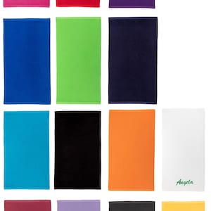 May include: A set of 12 towels in various colors, including pink, red, purple, blue, green, navy, turquoise, black, orange, white, maroon, lavender, gray, and yellow. One white towel has the name "Angela" embroidered on it.