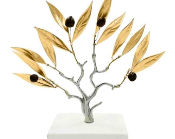 May include: A gold and silver olive branch sculpture with black olives on a white marble base. The sculpture is a decorative piece for a home or office.