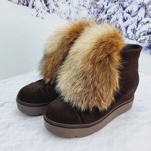 K&ouml;nnte beinhalten: Braune Wildlederstiefel mit dicker Plateau-Sohle und einem flauschigen Fuchs-Fellbesatz am oberen Rand des Stiefels.