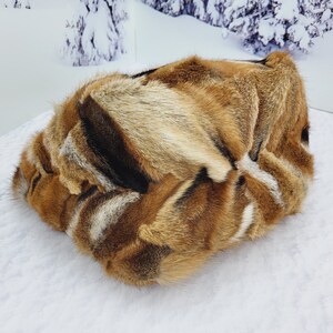 May include: A brown, black, and white fur throw pillow with a soft, fluffy texture.