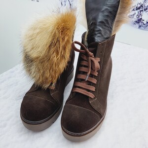K&ouml;nnte beinhalten: Ein Paar braune Wildlederstiefel mit Pelzbesatz. Die Stiefel haben Schn&uuml;rsenkel und eine dicke Plateau-Sohle.