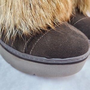 K&ouml;nnte beinhalten: Braune Wildlederstiefel f&uuml;r den Winter mit einem Kunstfellbesatz am oberen Rand des Stiefels. Die Stiefel haben eine dicke Gummisohle.