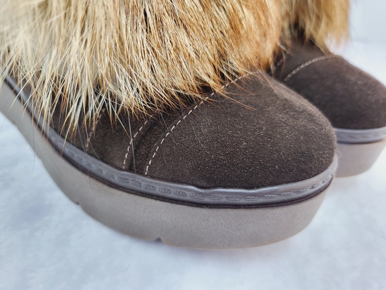 K&ouml;nnte beinhalten: Braune Wildlederstiefel f&uuml;r den Winter mit einem Kunstfellbesatz am oberen Rand des Stiefels. Die Stiefel haben eine dicke Gummisohle.