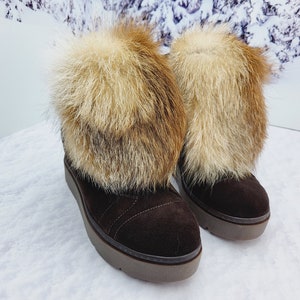 K&ouml;nnte beinhalten: Ein Paar braune Wildlederstiefel mit Kunstfellbesatz. Die Stiefel haben eine dicke Plateau-Sohle und sind mit Fell gef&uuml;ttert.