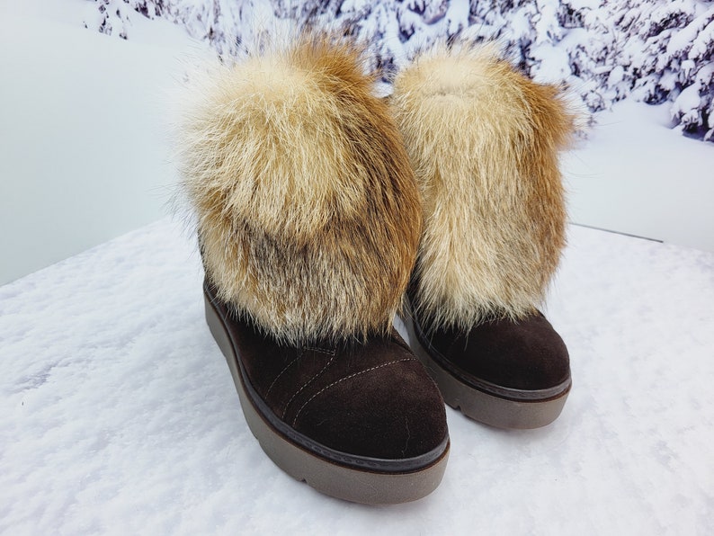 K&ouml;nnte beinhalten: Ein Paar braune Wildlederstiefel mit Kunstfellbesatz. Die Stiefel haben eine dicke Plateau-Sohle und sind mit Fell gef&uuml;ttert.