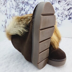 K&ouml;nnte beinhalten: Braune Wildlederstiefel mit Pelzbesatz am oberen Rand des Stiefels. Die Stiefel haben eine dicke Gummisohle mit einem Profilmuster.