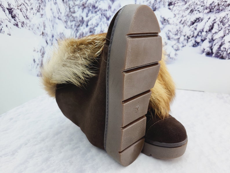 K&ouml;nnte beinhalten: Braune Wildlederstiefel mit Pelzbesatz am oberen Rand des Stiefels. Die Stiefel haben eine dicke Gummisohle mit einem Profilmuster.