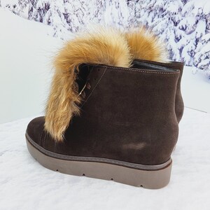 K&ouml;nnte beinhalten: Braune Wildlederstiefel mit einem Kunstfellbesatz am oberen Rand des Stiefels. Die Stiefel haben eine dicke Plateau-Sohle.