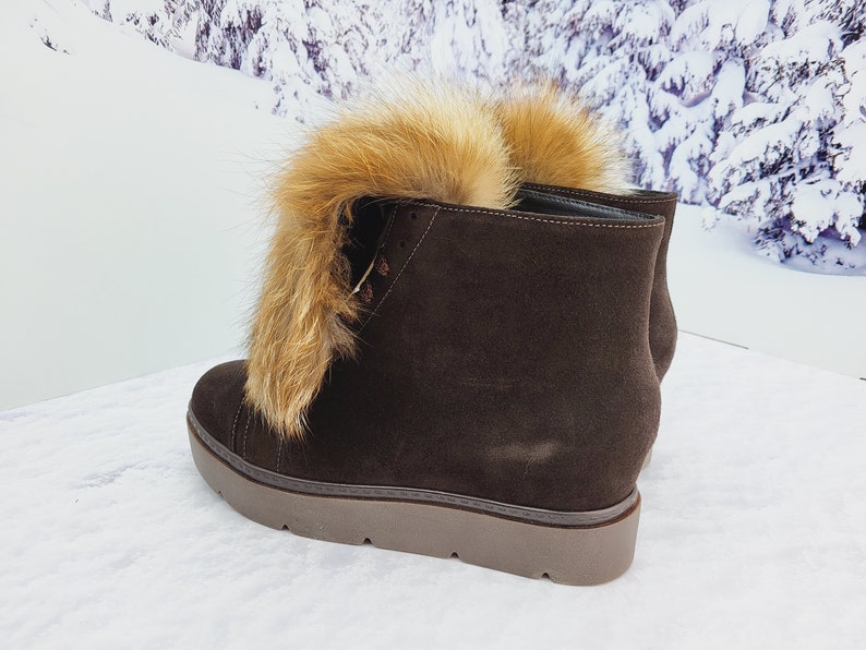 K&ouml;nnte beinhalten: Braune Wildlederstiefel mit einem Kunstfellbesatz am oberen Rand des Stiefels. Die Stiefel haben eine dicke Plateau-Sohle.