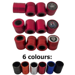 Könnte beinhalten: Eine Sammlung roter, zylindrischer Ventilkappen, einige mit dem Logo "Wolfsburg Edition". Das Bild zeigt auch sechs Farboptionen: Grau, Orange, Silber, Rot, Blau und Schwarz. Die Kappen haben eine schwarze Innenseite.