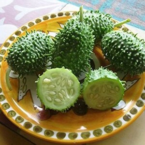 May include: A plate of green spiky fruits, some whole and some cut in half, revealing white seeds. The plate is yellow with a brown and white design.