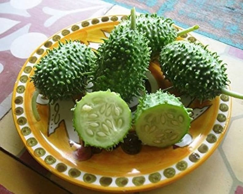 May include: A plate of green spiky fruits, some whole and some cut in half, revealing white seeds. The plate is yellow with a brown and white design.