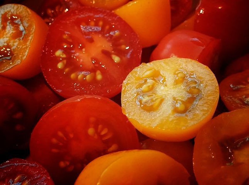 May include: Close-up of halved red and yellow tomatoes. The tomatoes are ripe and juicy, with visible seeds and a vibrant color palette. The image highlights the textures and freshness of the produce.