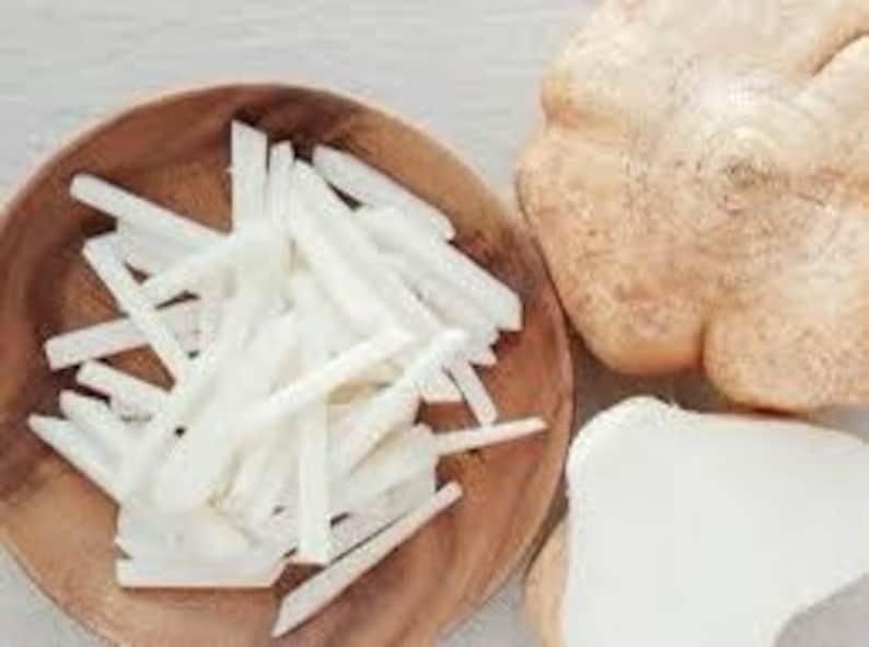 K&ouml;nnte beinhalten: Eine Holzschale gef&uuml;llt mit wei&szlig;en, julienne-geschnittenen Jicama. Neben der Schale befinden sich eine ganze Jicama und ein St&uuml;ck Jicama. Die Jicama hat eine hellbraune Schale und ein wei&szlig;es Inneres. Die Schale ist rund und aus Holz.