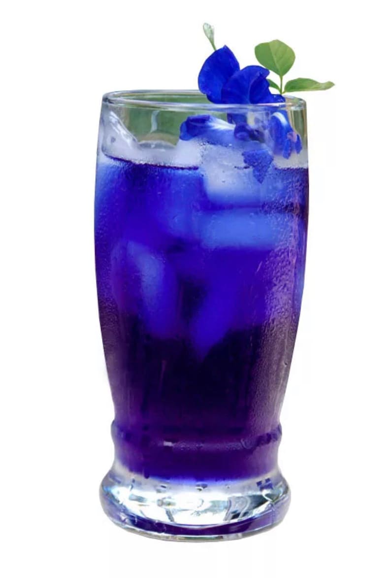 May include: A tall glass filled with a vibrant blue beverage, ice cubes, and garnished with blue flowers and green leaves. The drink appears refreshing and is set against a white background.