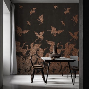 May include: A dining room with a dark grey wall featuring a wallpaper pattern of copper-coloured cranes. The wallpaper has a textured look and the cranes are in various sizes and positions. A wooden table with two chairs is in the foreground.