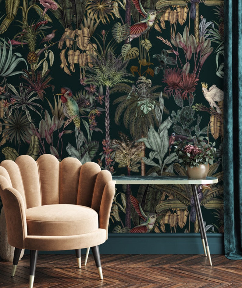 May include: A beige velvet armchair with a scalloped back and tapered legs sits before a dark green wallpaper featuring a dense jungle pattern of tropical palm leaves, exotic flowers, colorful hummingbirds, and a white cockatoo perched on a branch.
