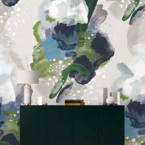 May include: A dark green cabinet with white legs stands in front of a wall with an abstract wallpaper design. The wallpaper features large, overlapping brushstrokes in shades of green, blue, and white, creating a dynamic and modern look.
