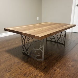 May include: A wooden table with a natural wood finish and a unique metal base that resembles tree branches. The table is in a room with hardwood floors.