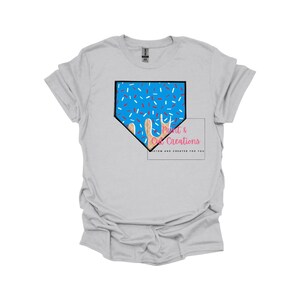 May include: A light gray t-shirt with a blue and white baseball diamond design with sprinkles. The text "Print & Cut Creations" is in pink and white.