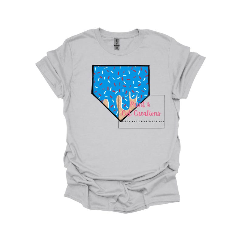 May include: A light gray t-shirt with a blue and white baseball diamond design with sprinkles. The text "Print & Cut Creations" is in pink and white.