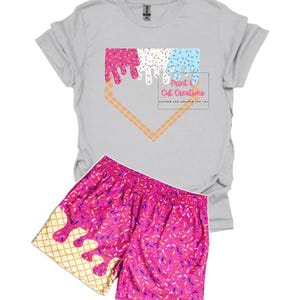 May include: A gray t-shirt with a pink, blue, and white ice cream cone graphic in the shape of a baseball diamond. The text "Print & Cut Creations" is below the graphic. A pair of pink athletic shorts with a matching ice cream cone graphic.