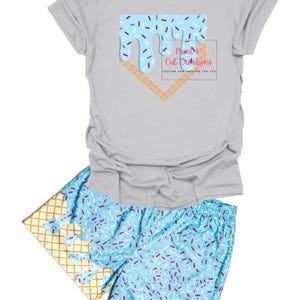 May include: A gray t-shirt with a blue and white ice cream cone graphic and the text "Print & Cut Creations" in pink. Matching blue and white shorts with a waffle cone pattern and sprinkles.