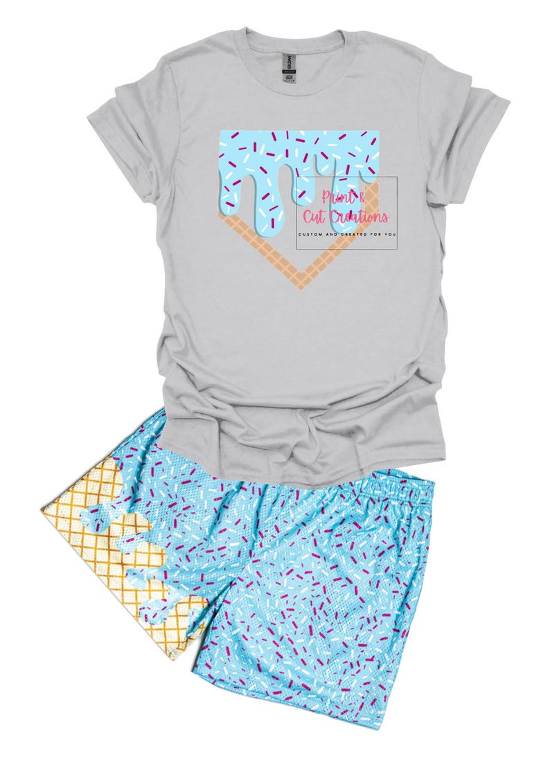 May include: A gray t-shirt with a blue and white ice cream cone graphic and the text "Print & Cut Creations" in pink. Matching blue and white shorts with a waffle cone pattern and sprinkles.