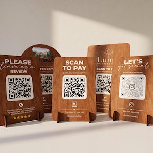 Puede incluir: Una colección de cinco letreros verticales de madera con esquinas redondeadas, cada uno con un código QR impreso y texto. Los letreros muestran varias indicaciones, incluyendo Please leave us a review, Scan to pay y Let's get social, sobre soportes de madera.