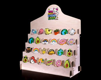 May include: A light-colored wooden tiered display stand featuring four shelves filled with various colorful stickers. The top header displays the text YOUR AWESOM STICKER LOGO with a cartoon cat illustration. The stickers depict items like avocados, rainbows, planets, and donuts.