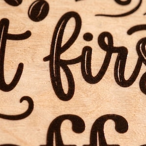 Macro close-up showing sharp, detailed UV printed black lettering on natural birch plywood with a visible wood grain texture.