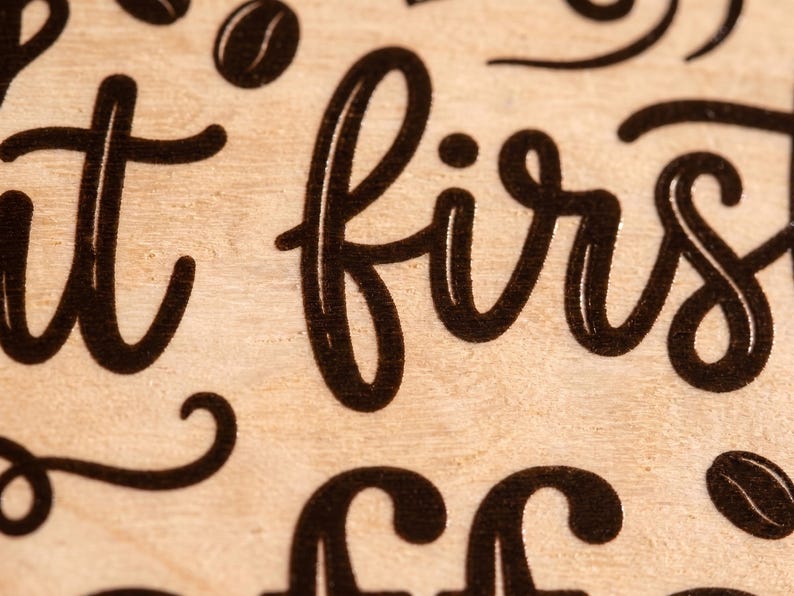 Extreme close-up of a custom quote sign showing precise black UV printed lettering directly on the natural wood grain.