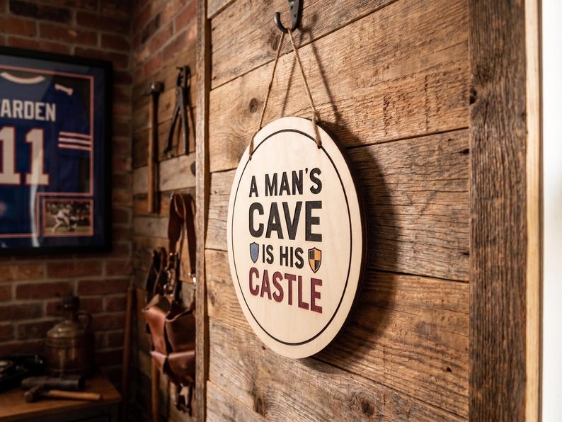 Personalized round wood sign hanging on a rustic wooden wall with printed text reading A Man's Cave Is His Castle.