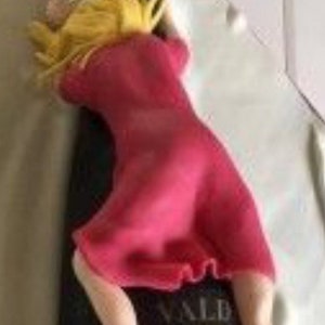 Könnte beinhalten: Ein rosa Kuchen, der wie eine Frau aussieht, die auf einer Flasche Prosecco sitzt.