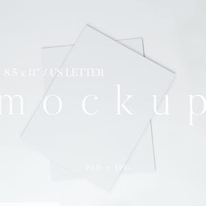 May include: Two white 8.5 x 11 inch US Letter mockups are slightly overlapping on a white background. The word "mockup" is written in a delicate font across the center of the image. The text "PSD + JPG" is at the bottom.