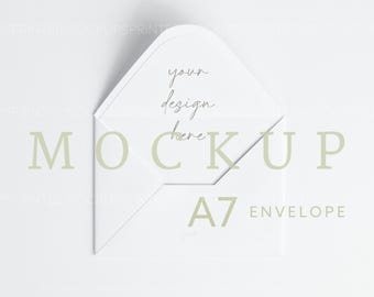 Op de afbeelding: Witte A7-envelop mockup met de tekst "your design here" in cursief op de voorkant. De envelop ligt plat op een wit oppervlak.
