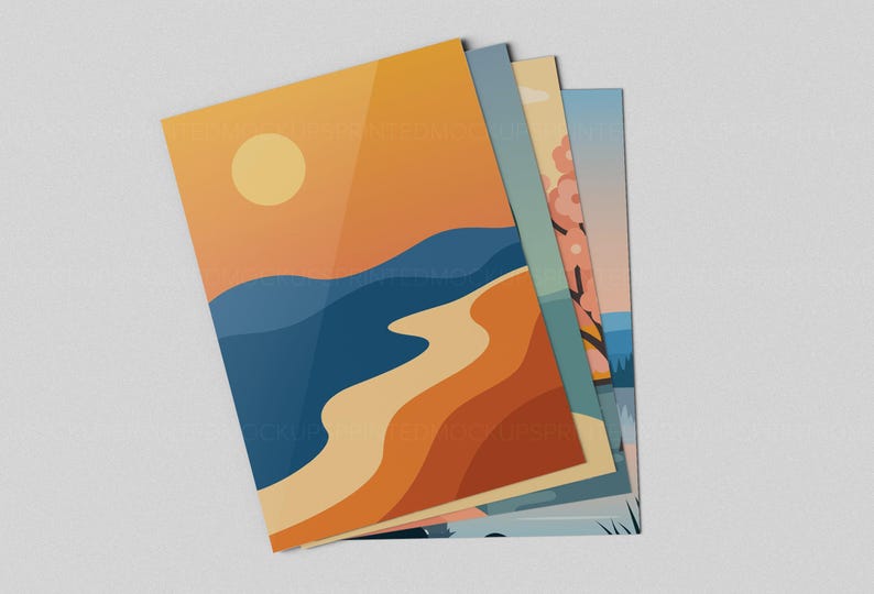 May include: A stack of art prints featuring minimalist landscape designs. The prints showcase a sunset over the ocean, a beach scene, and a tree with pink blossoms. The color palette includes shades of orange, blue, and beige.