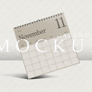 Puede incluir: Una maqueta de calendario beige con el mes de noviembre de 2023 y el número 11 resaltado. El texto "CALENDAR MOCKUP" está impreso en blanco en la imagen.