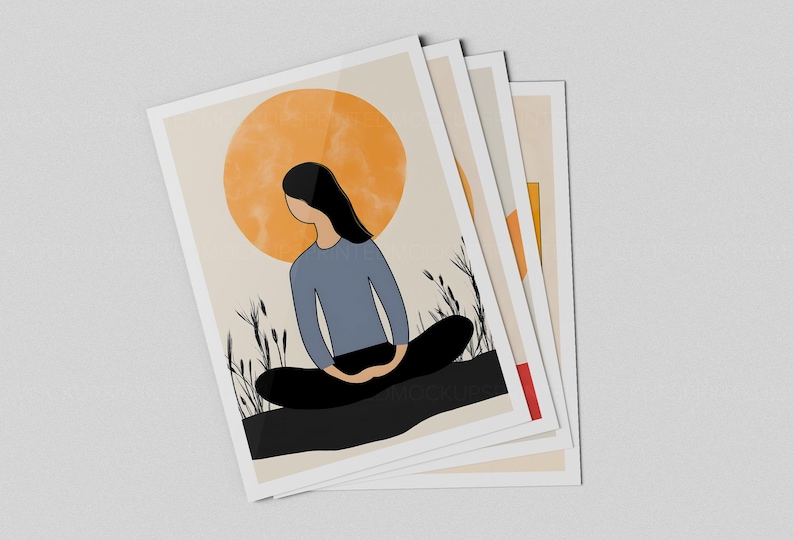May include: A stack of art prints featuring a minimalist illustration of a person meditating. The artwork depicts a figure in a blue shirt and black pants, with a large orange sun in the background. The prints have a white border.